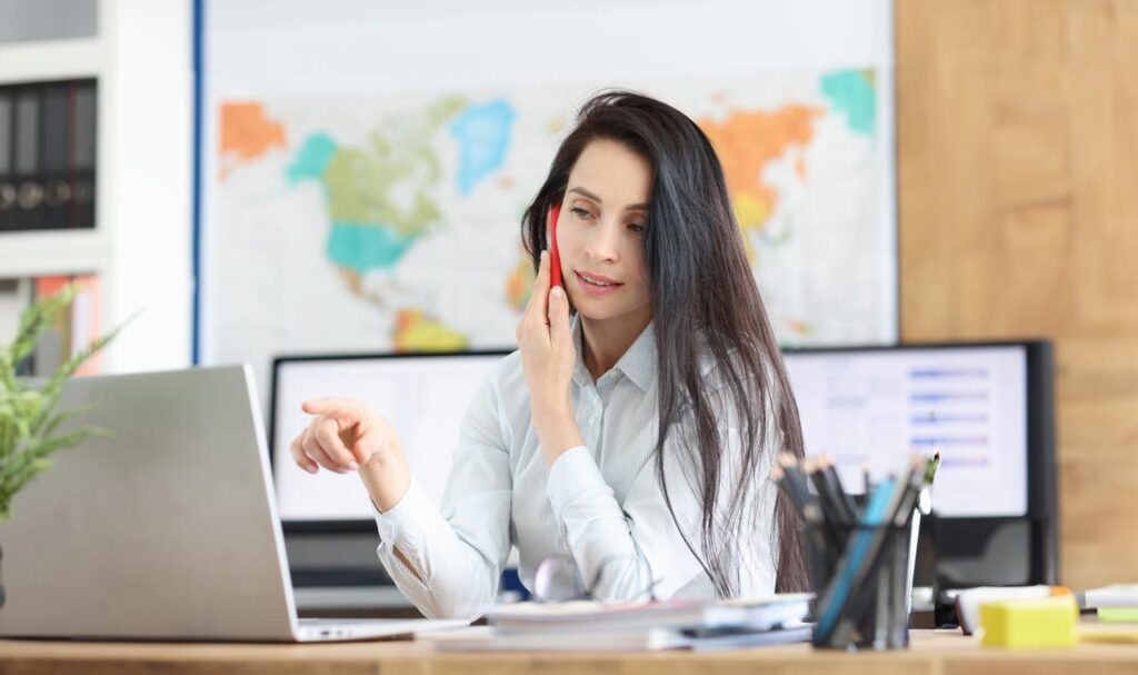 consultor de negocios hablando positivamente por teléfono móvil trabajando con portátil en oficina